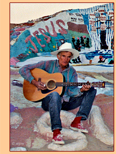 <Photo by Wolf Peter Weber of Leonard Knight as guitarist and singer in front of his Salvation Mountain>